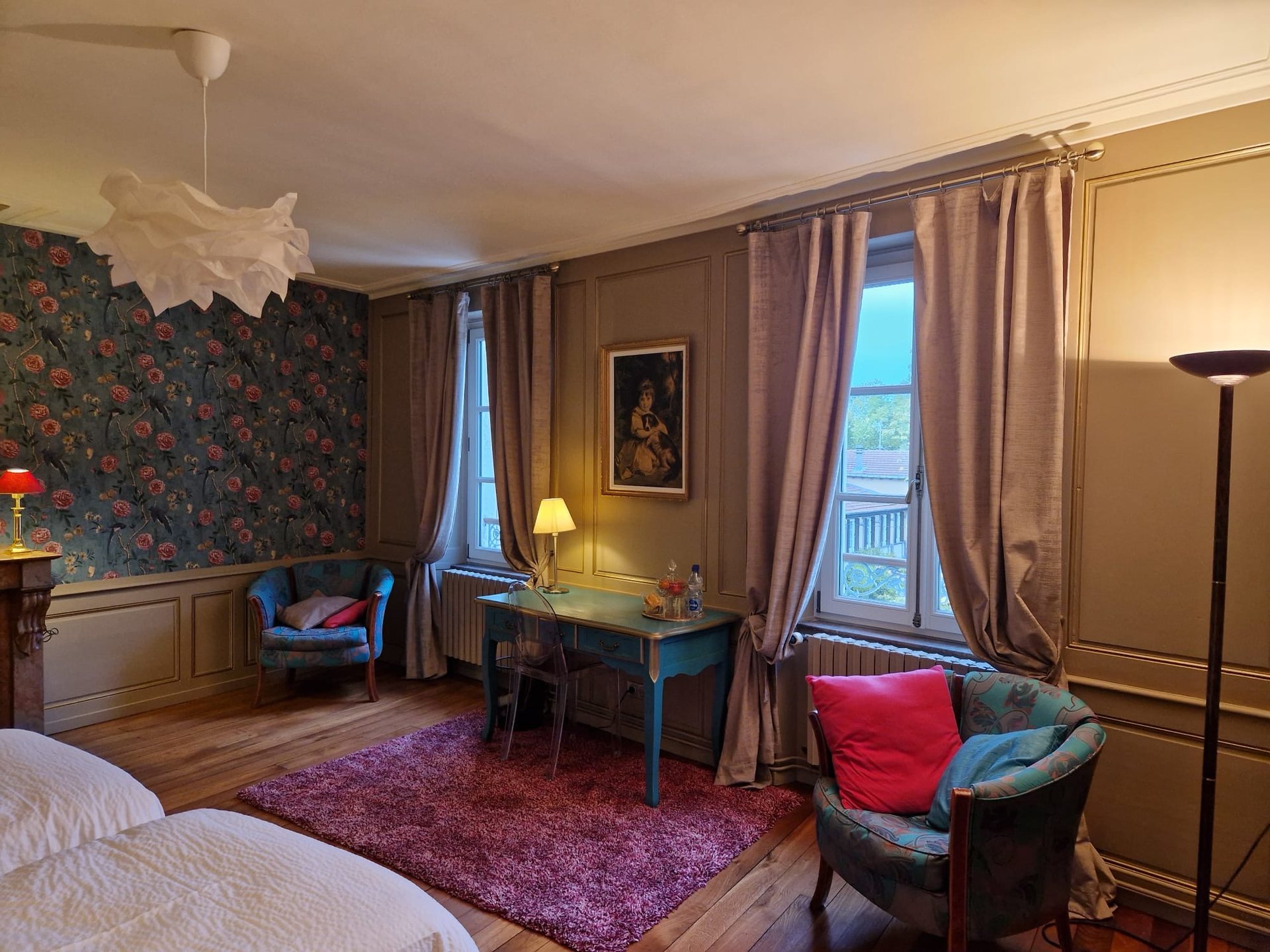 Coin salon de la chambre Cupidon : fauteuils, bureau et grandes fenêtres