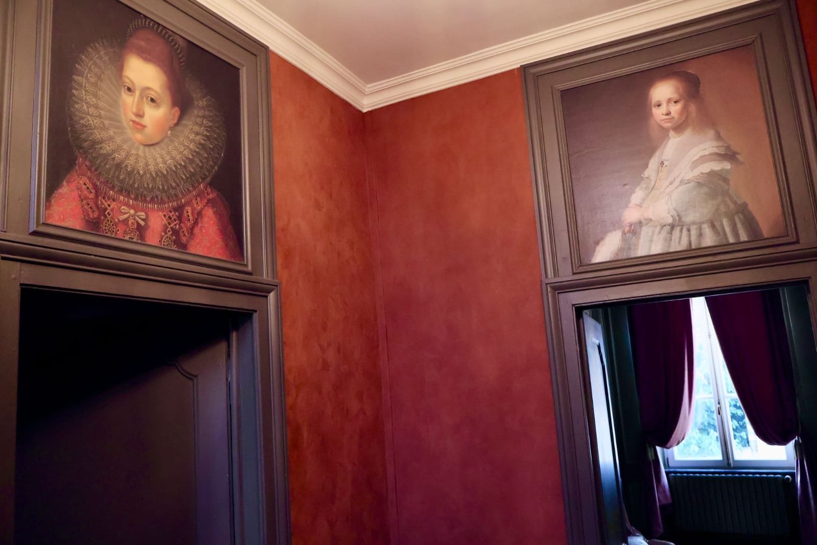 Couloir de La Balsamine aux murs terracotta et portraits anciens