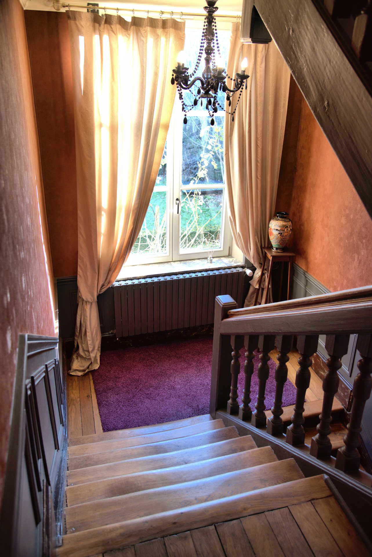 Escalier de bois et fenêtre habillée de rideaux à La Balsamine